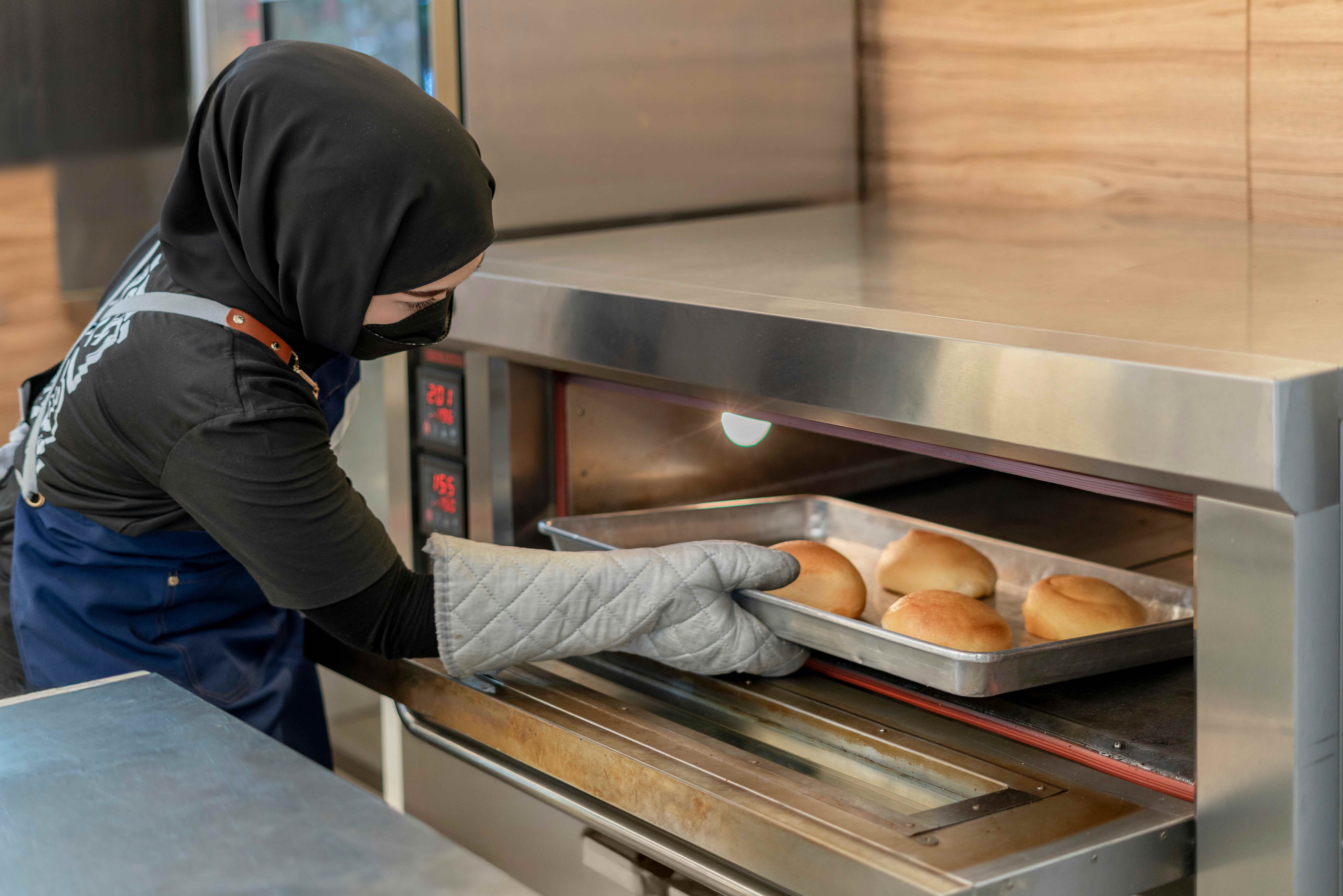 Baker taking fresh bread from the oven